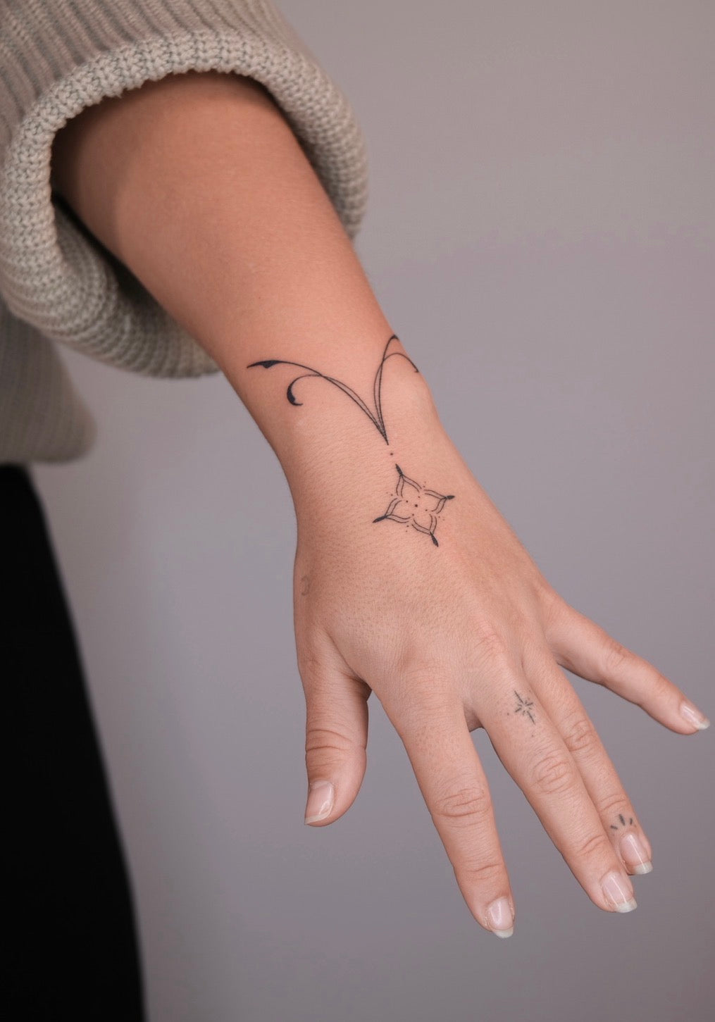 Filigranes handpoke Tattoo mit feinen Linien Armband am Handgelenk mit Fingertattoos