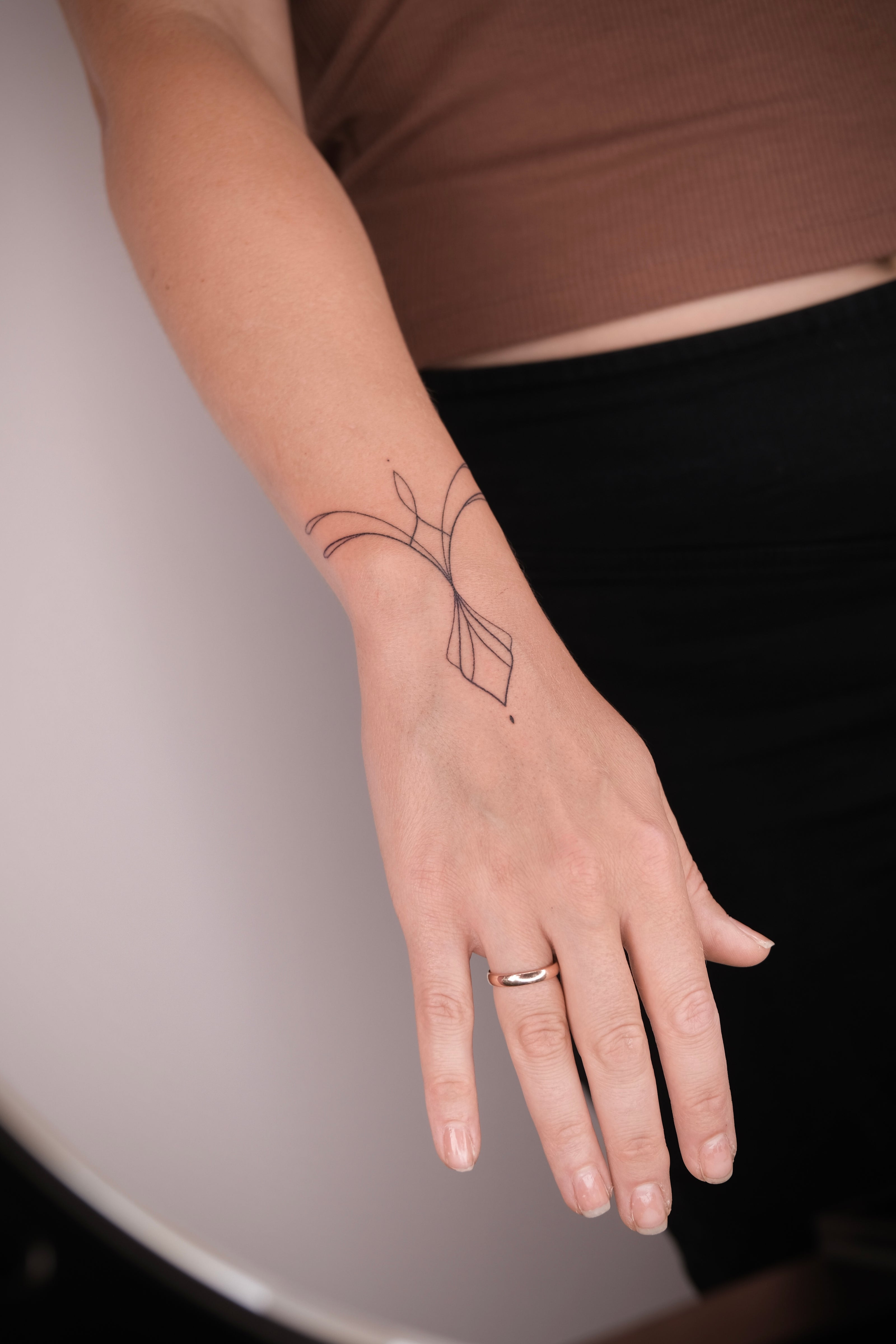 Minimalistisches handgestochenes Fineline Armband Tattoo am Handgelenk 
