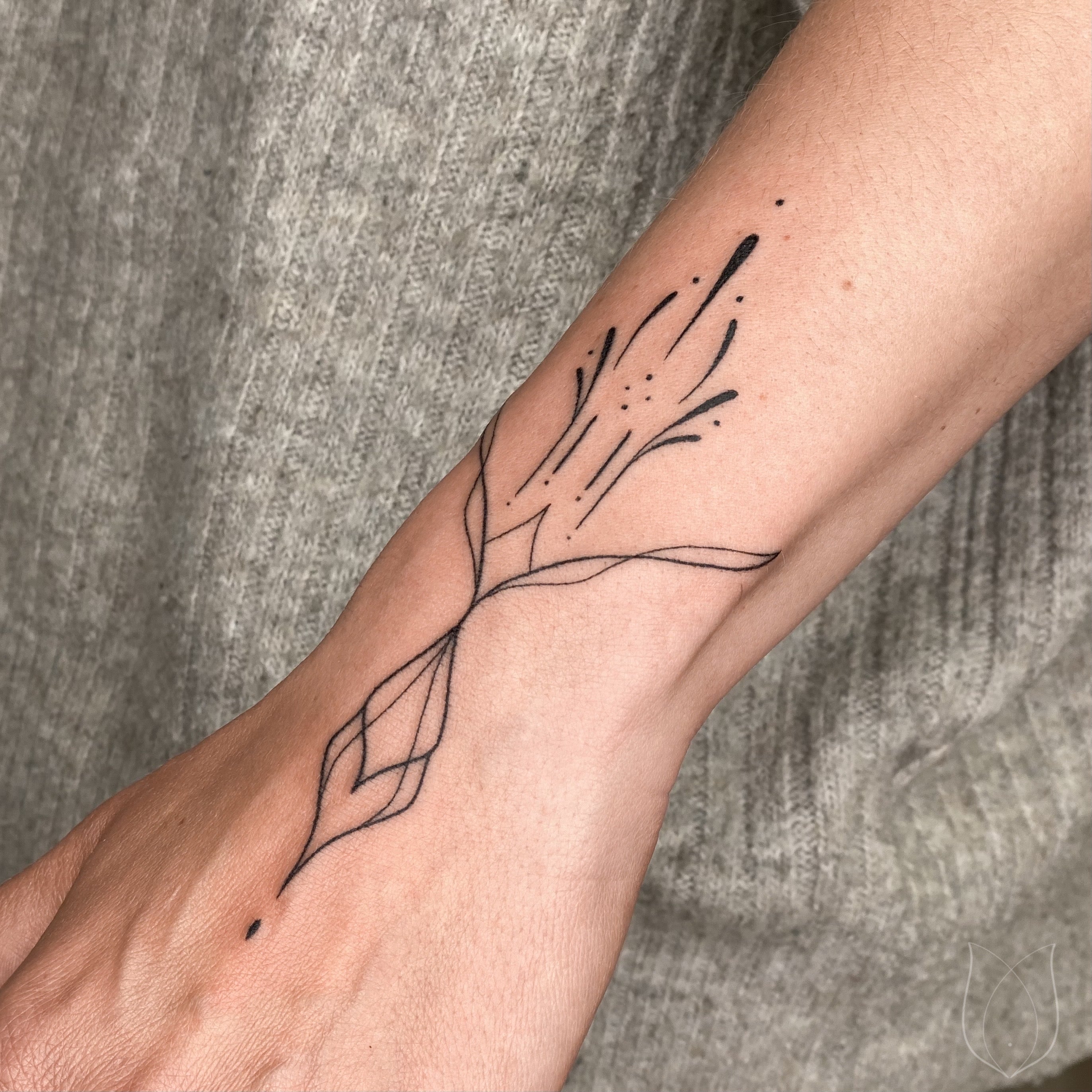 Filigranes Fineline Handpoke Tattoo mit klaren Linien am Handgelenk
