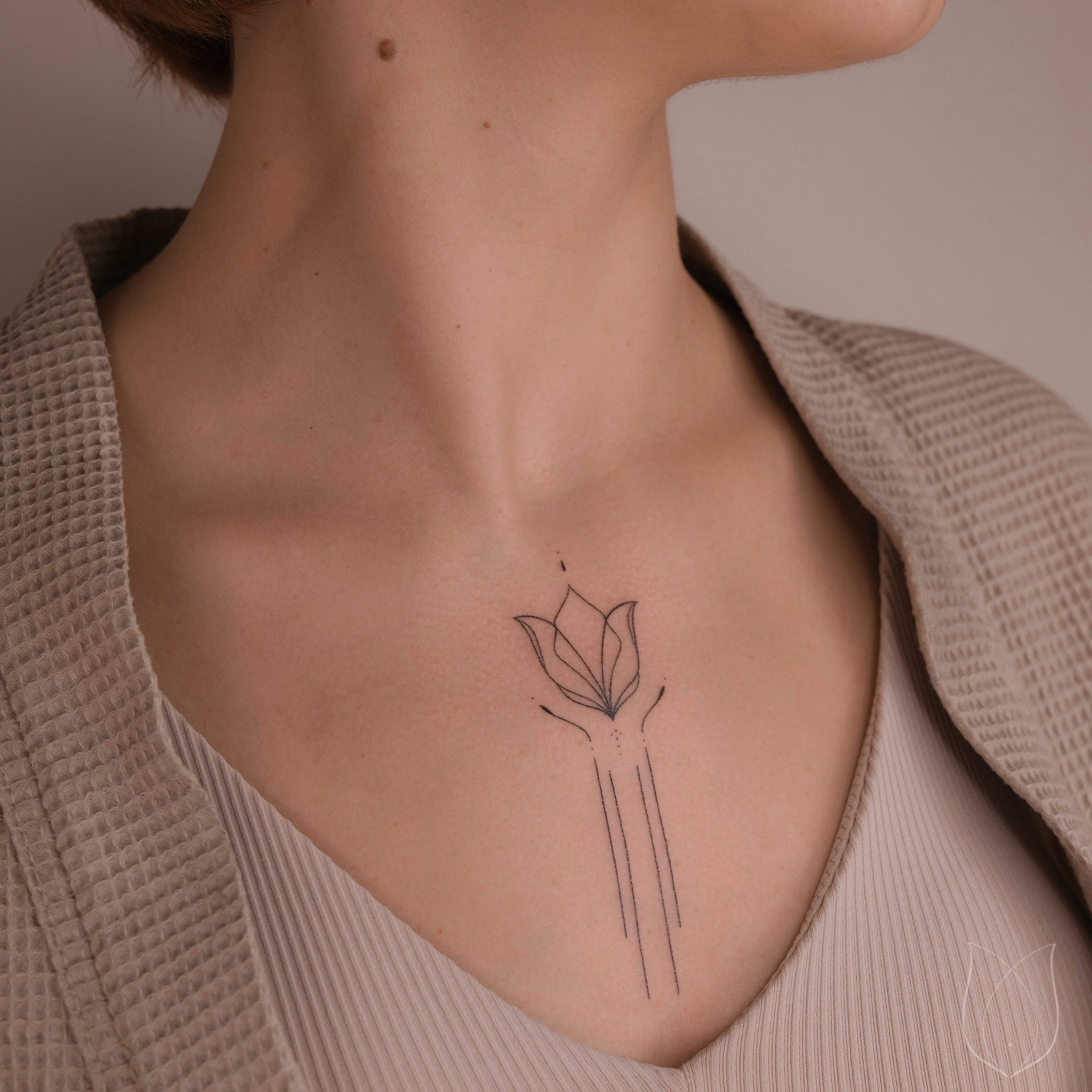 handgestochenes finelinetattoo Lotus im Décolleté
